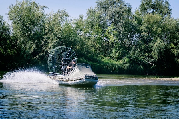 Szybka jazda łodzią powietrzną po rzece w letni dzień z rozpryskami i falami