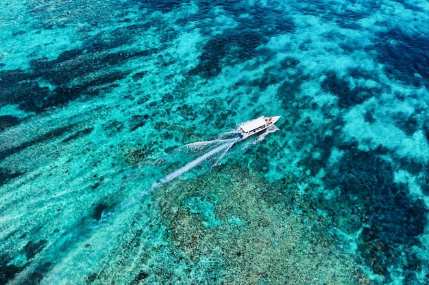 Szybka łódź na morzu w Bali Indonezja Widok z lotu ptaka luksusowej łodzi pływającej na przezroczystej turkusowej wodzie w słoneczny dzień Pejzaż morski z powietrza Widok z góry z drona Obraz podróży