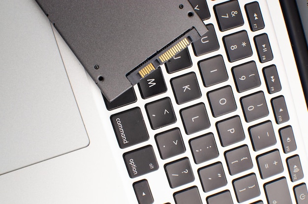 Szybka pamięć masowa SSD na szarym laptopie z technologią SSD Concept informatyka wydajność i innowacyjność i wydajność Dysk SSD o białej powierzchni z portem i złotym złączem
