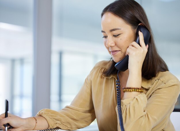 Szybkie rozwiązywanie problemów Ujęcie młodej bizneswoman piszącej notatki podczas rozmowy przez telefon w biurze