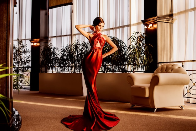 Zdjęcie szykowny efektowny model w długiej czerwonej sukience wieczorowej.