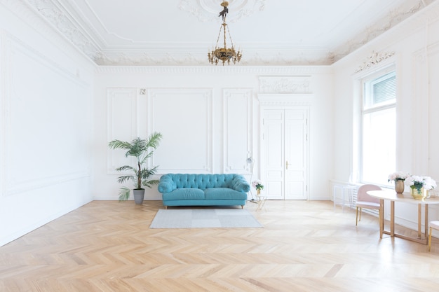 Szykowny przestronny jasny pokój w starej rezydencji w stylu klasycznym z XIX wieku z wysokim sufitem ozdobionym sztukaterią na białych ścianach