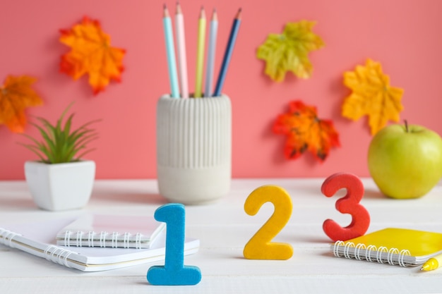 Zdjęcie tabela z numerami przybory szkolne szkło powiększające zeszyty zeszyty budzik i ołówki