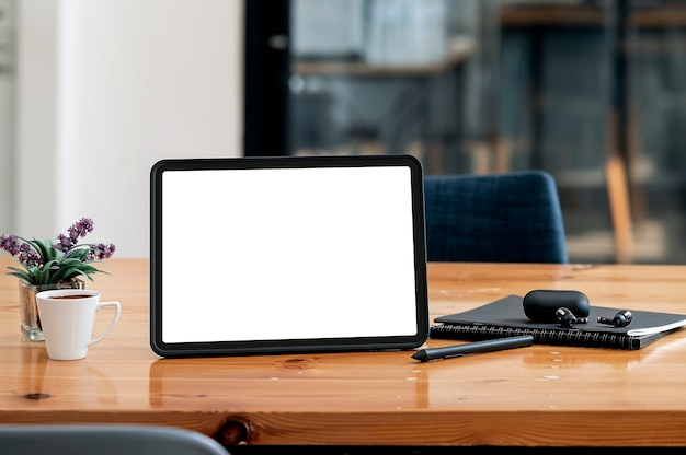 Tablet z pustym ekranem i gadżet na drewnianym stole w pokoju biurowym z miejscem na kopię