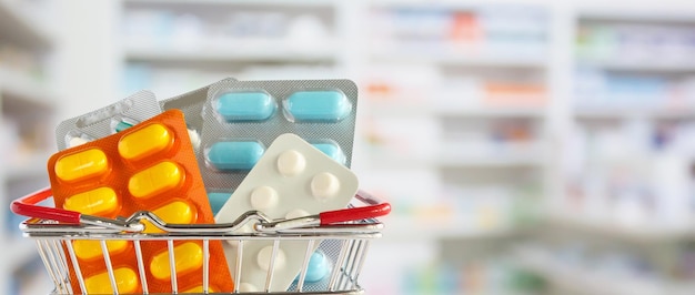 Tabletka z pigułkami medycznymi w koszyku na zakupy z półkami apteki w aptece rozmazanym tłem