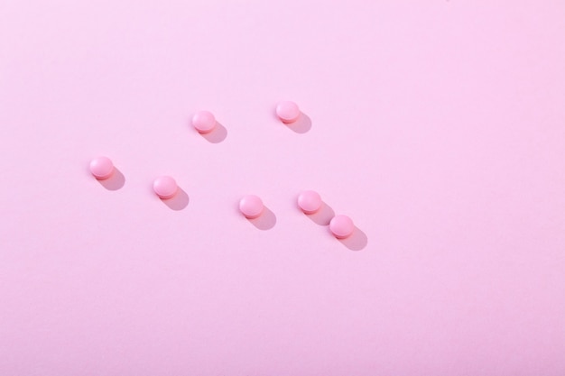 Tabletki i pigułki, witaminy i antybiotyk na różowym tle, miejsce