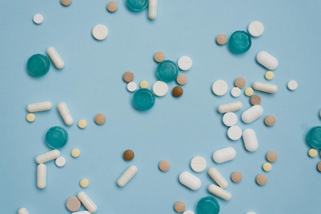 Tabletki luzem są wielokolorowe na niebieskim tle Koncepcja apteki medycyny