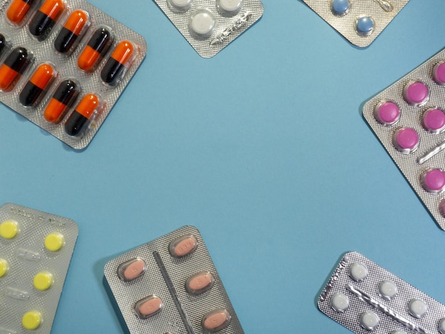 Tabletki w różnych kolorach na niebieskim tle Koncepcja leków Miejsce na napis Leczenie medyczne Wzór blistra pigułki