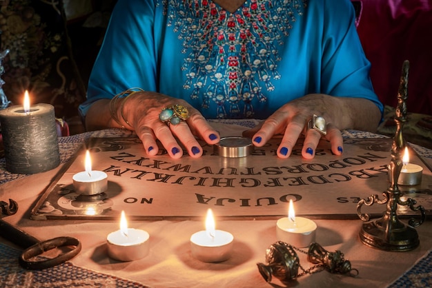 Tablica Ouija z rękami spirytualisty wróżki lub medium na stole przywołującego duchy