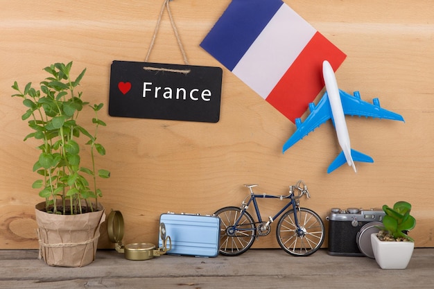 Zdjęcie tablica z tekstem flaga francji francuskiego modelu samolotu mały rower i aparat walizkowy