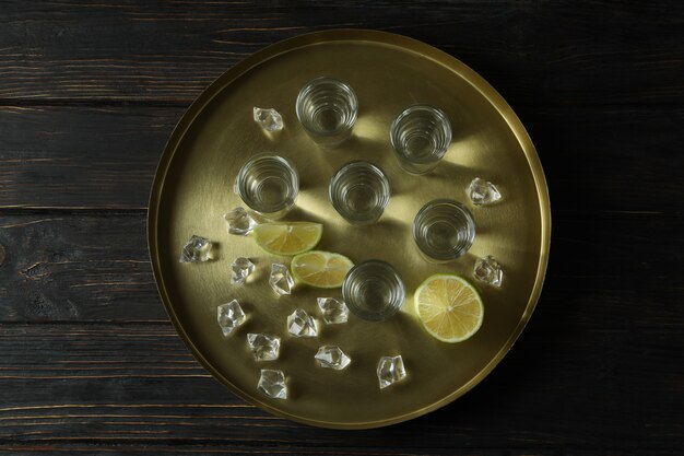 Zdjęcie taca z shotami, plasterkami limonki i kostkami lodu na drewnianym stole