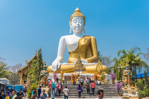 Tajlandzcy pielgrzymi cześć i turysta w dużej siedzącej Buddha statui