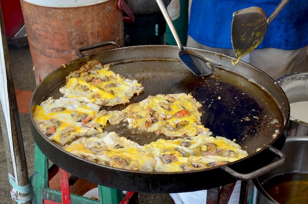 Tajowie gotują smażone małże z jajkiem i chrupiącą mąką lub omlet ostrygowy na sprzedaż na targu