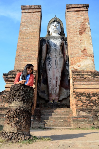 Tajska kobieta podróżuje i portret ze starym wielkim posągiem Buddy i starożytnym budynkiem w historycznym mieście Sukhothai i powiązanych historycznych miastach w Sukhothai w Tajlandii