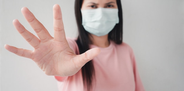 Zdjęcie tajska kobieta ubrana w maskę za pomocą dłoni, aby pokazać zatrzymanie koronawirusa
