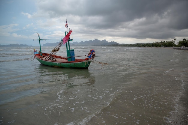 Tajska łódź z długim ogonem podczas odpływu na oceanie z krasowymi górami w tle i chmurą w Tajlandii Azja
