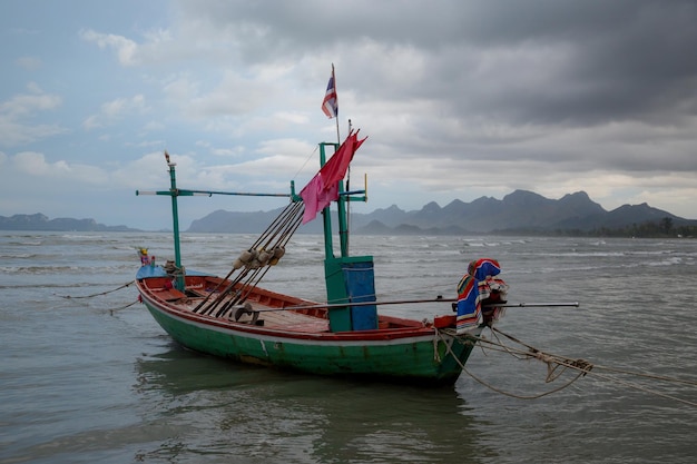 Tajska łódź z długim ogonem podczas odpływu na oceanie z krasowymi górami w tle i chmurą w Tajlandii Azja