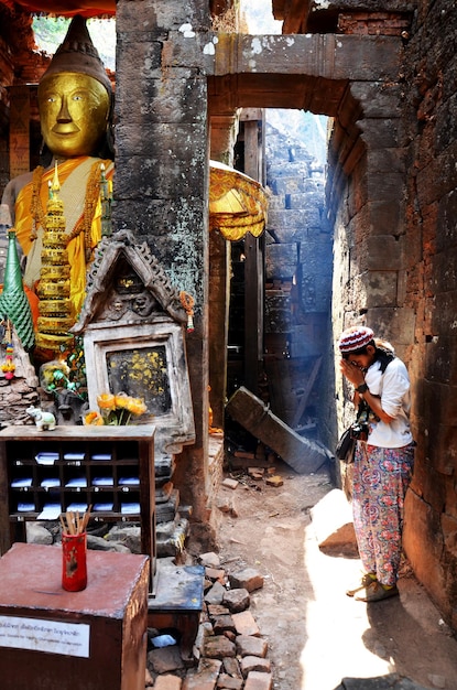 Tajski kobieta modląc się ruiny posąg Buddy obrazu w Vat Phou lub Wat Phu stanowiska archeologicznego wpisanego na listę światowego dziedzictwa UNESCO w Pakse Champasak Laos