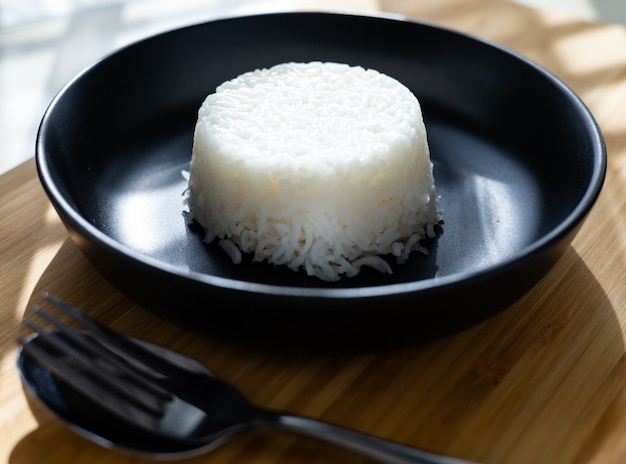 Tajski styl gotowania ryżu parowego umieścić na czarnej płycie na drewniane tła z parą sztućce widelec.