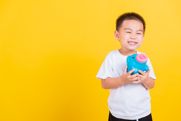 Tajski szczęśliwy portret ładny mały wesoły chłopiec dziecko uśmiech trzymając skarbonkę