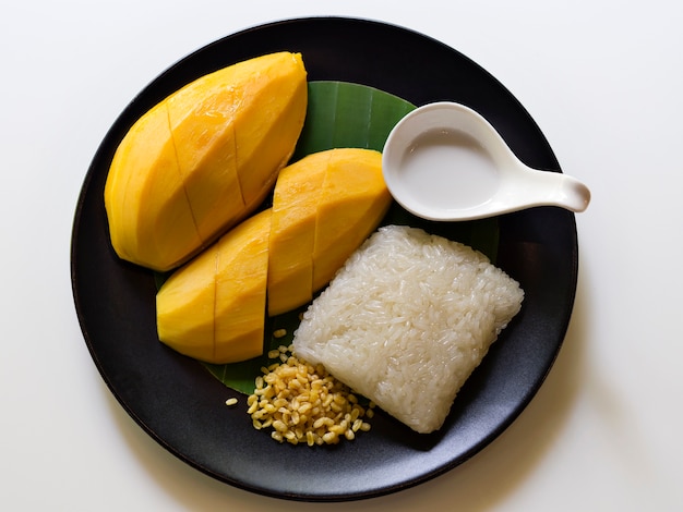 Tajski tradycyjny deser, słodkie plastry mango podawane z lepkim ryżem i mlekiem kokosowym