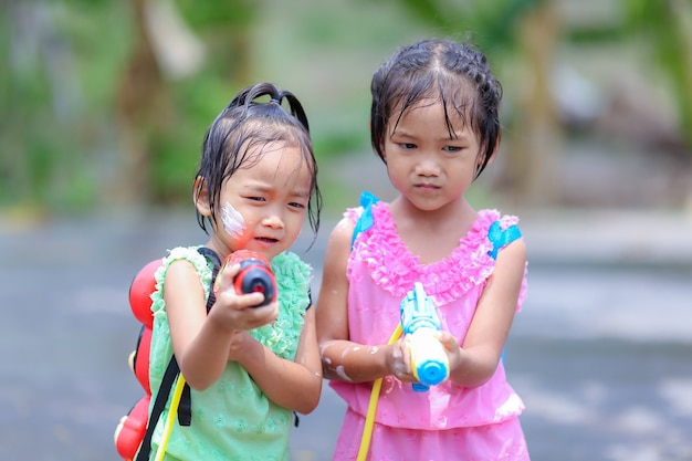 Tajskie dziewczęta dzieci grające w pistolety wodne na festiwalu songkran z tajskimi strojami z epoki
