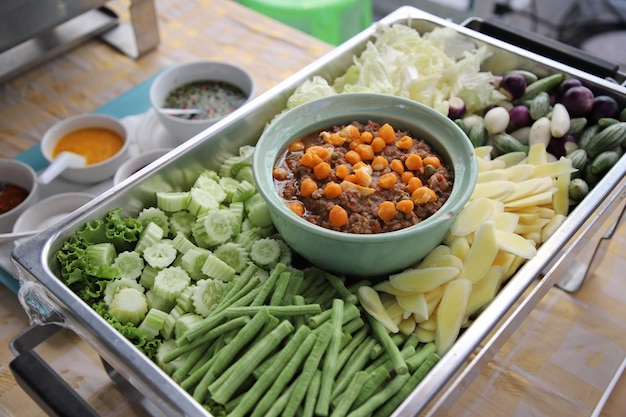 Tajskie jedzenie, Nam Prik Kai Poo (Crab's Roe Chilli Dip) z wieloma rodzajami warzyw w bufecie. Pojemnik to prostokątna taca ze stali nierdzewnej. Selektywne skupienie.