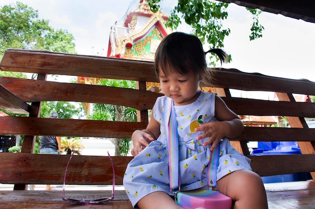 Tajskie Małe Dzieci Dziewczynka Siedzą Odpoczywają Na ławce I Bawią Się Po Podróży Odwiedzają Modlącego Się Buddę Z Rodziną Rodziców W świątyni Wat Kositaram Lub Ban Khae 27 Maja 2020 R. W Chai Nat Tajlandia
