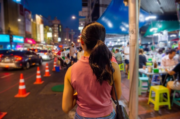 Tajsko-chińscy turyści spacerują i próbują ulicznego jedzenia na Yaowarat Road w Chinatown w Bangkoku