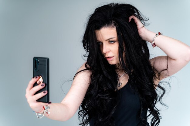 Tak niebezpieczna Brunetka kobieta patrząca w kamerę podczas robienia selfie na swoim smartfonie Zdjęcie stockowe