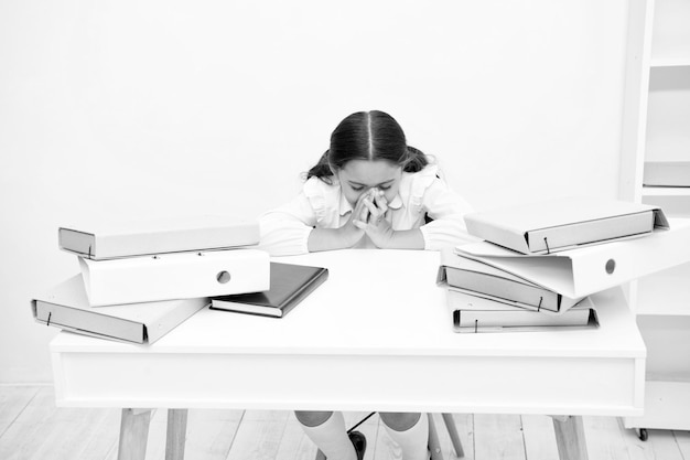 Tak zdenerwowana przed nadchodzącym testem Dziewczynka czyta książkę siedząc przy stole na białym tle Uczennica studiuje przygotowuje się do testu lub egzaminu Dzieciak dziewczyna mundurek szkolny zdenerwowana przed nadchodzącym testem sprawdza wiedzę