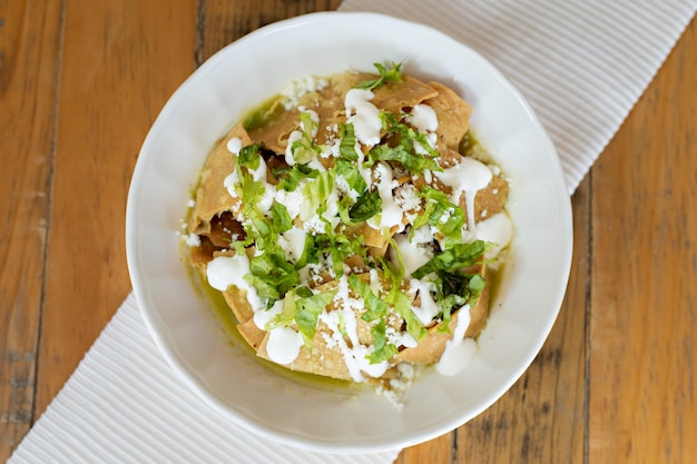 Talerz Chilaquiles Serwowane Na Białym Talerzu Przygotowanym Z Chipsów Kukurydzianych, Sałatą Kremową I Serem