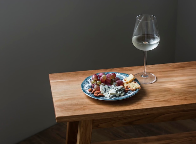 Talerz przystawek z krakersem z winogron gorgonzola i kieliszkiem białego wina na drewnianym stole