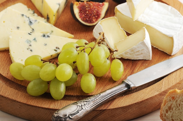Talerz serów z różnymi rodzajami serów, fig i winogron na białej drewnianej powierzchni
