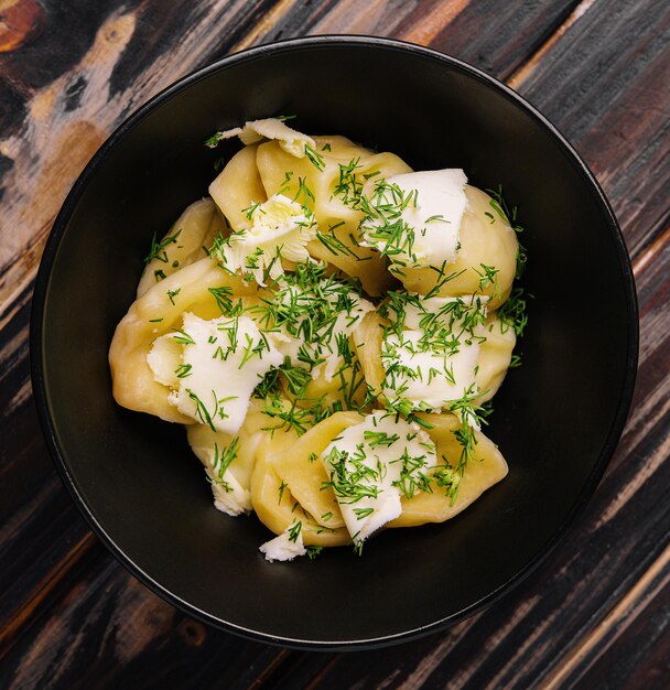 Talerz smacznych gotowanych pierogów na czarnym talerzu