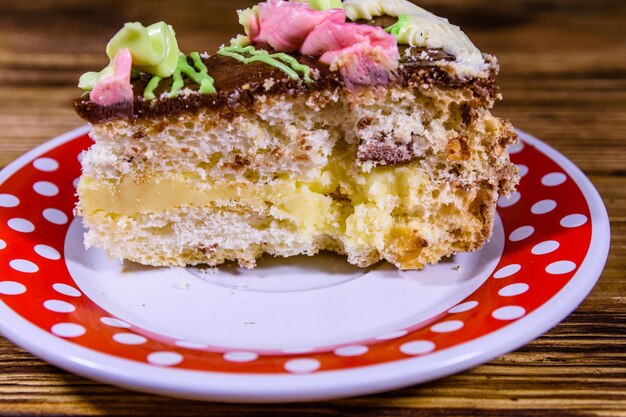 Zdjęcie talerz z kawałkiem ciasta kijowskiego ze śmietaną, orzechami i bezą na drewnianym stole
