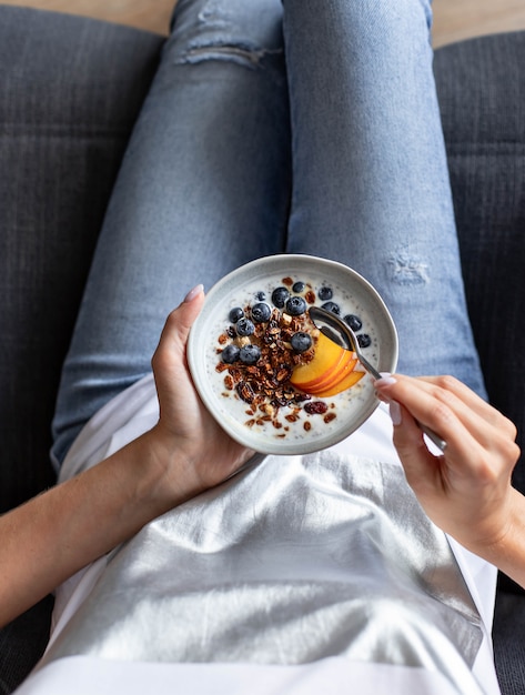 Talerz z muesli i świeżymi jagodami w rękach młodej dziewczyny