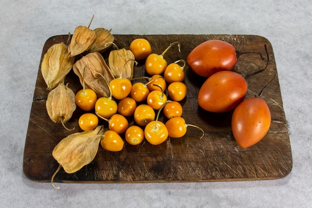 tamarillo lub pomidor z drzewa na desce obok uvilla lub aguaymanto physalis