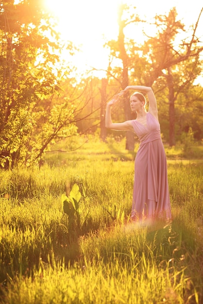 Tancerka w sukience w ogrodzie botanicznym tańczy latem o zachodzie słońca