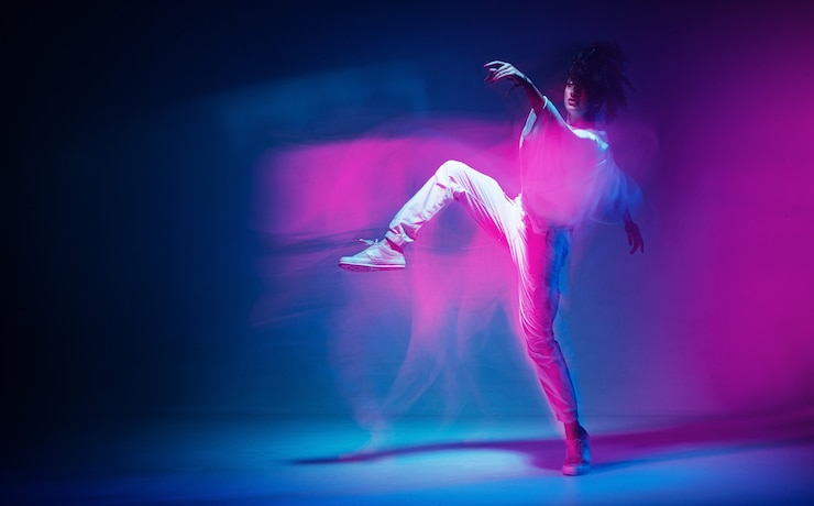 Zdjęcie tańcząca sportowa kobieta w kolorowym neonowym świetle ekspresyjnym fotografią studia tańca współczesnego z