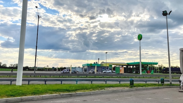 Tankowanie samochodów na autostradzie na tle pięknego nieba z chmurami i promieniami słońca. Pojęcie kontrastu działalności człowieka i natury
