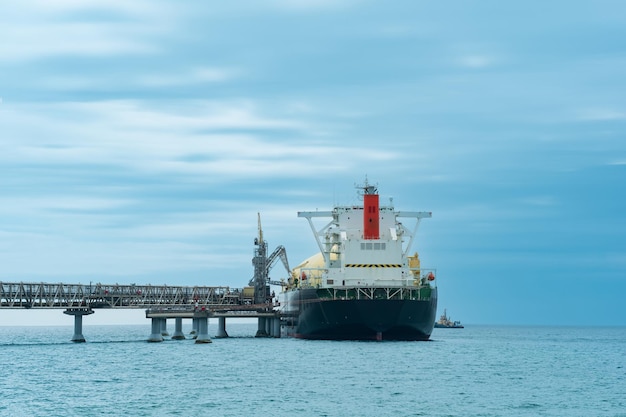 Tankowiec do przewozu skroplonego gazu ziemnego podczas załadunku na podmorskim terminalu LNG w odległości od terminalu eksportu ropy naftowej widocznego w morzu