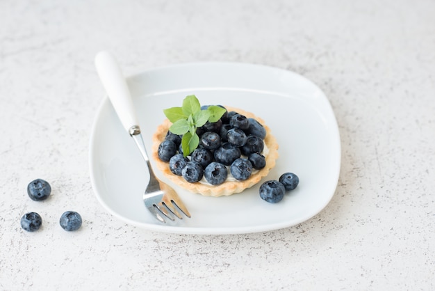 Tarta jagodowa ze śmietaną, sernik z jagodami na talerzu