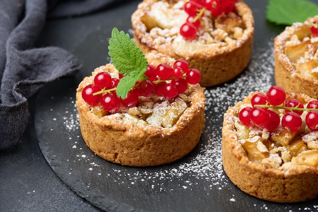 Tarta owocowa z czerwonymi porzeczkami posypana cukrem pudrem na czarnym stole