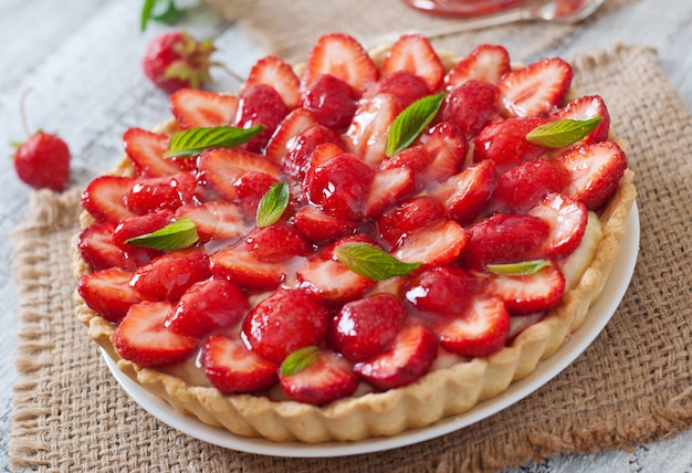 Tarta z truskawkami i bitą śmietaną ozdobiona liśćmi mięty