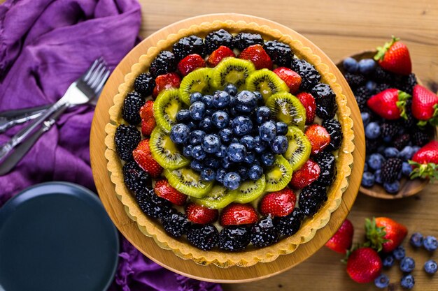 Zdjęcie tarta ze świeżych owoców na ciasto stoją na stół z drewna.