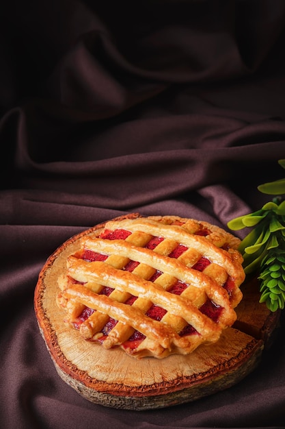 Tartlet lub tarta wypełniona domowym pysznym dżemem truskawkowym na brązowym drewnie i szmatce na przekąskę