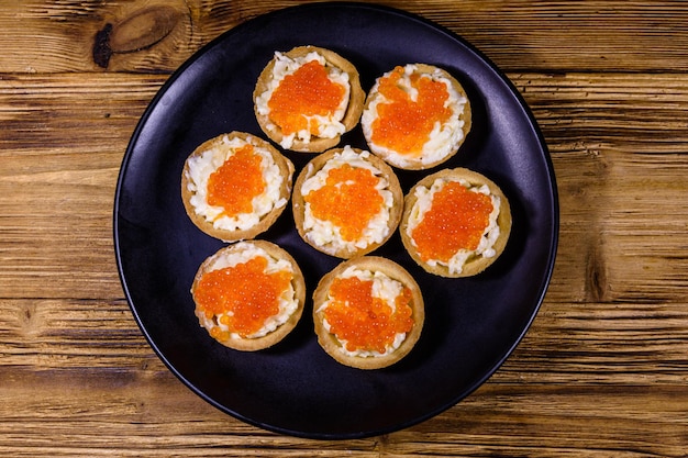 Tartlets z czerwonym kawiorem na czarnym talerzu. Świąteczne jedzenie. Widok z góry