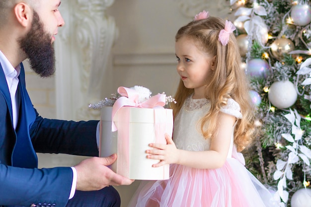 Tata daje córce prezent gwiazdkowy. ojciec gratulujący noworocznemu dziecku. szczęśliwe dzieciństwo. człowiek z pudełko z dziewczyną na Boże Narodzenie.