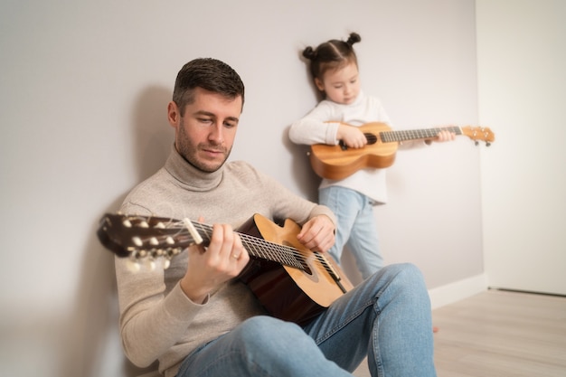 Tata Gra Na Gitarze Z Córką. Dziecko Uczy Się Gry Na Instrumencie Muzycznym Z Nauczycielem. Muzyczny Duet Ojca Z Dzieckiem.